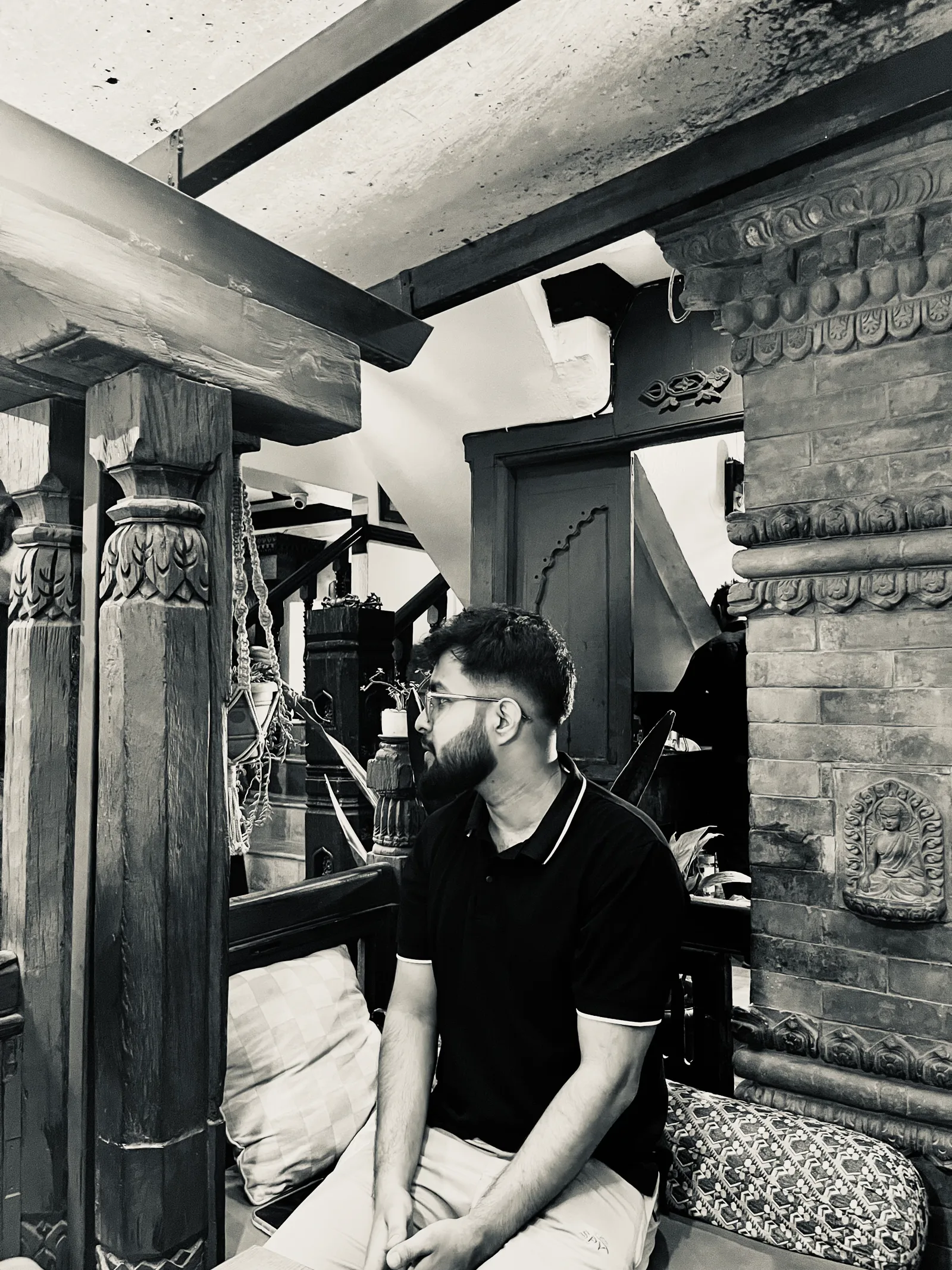 Janak Pokharel seated in traditional Nepali carved-wood architecture in Kathmandu